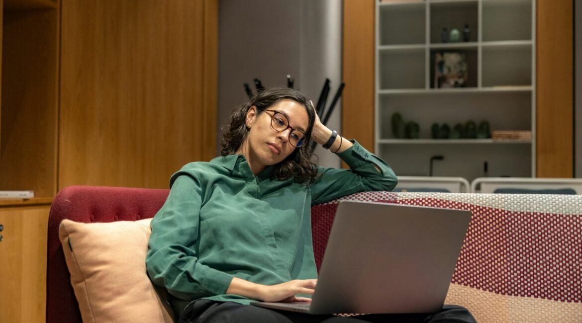 a woman sitting on a couch using a laptop computer